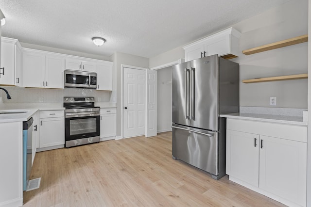 kitchen featuring light wood-type flooring, stainless steel appliances, sink, backsplash, and white cabinets