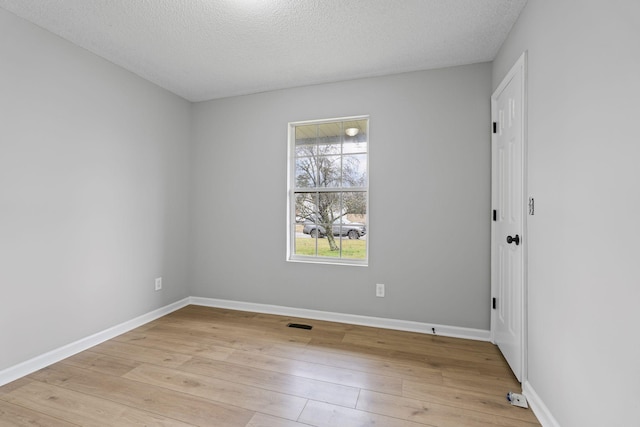 unfurnished room featuring light wood-type flooring and a textured ceiling