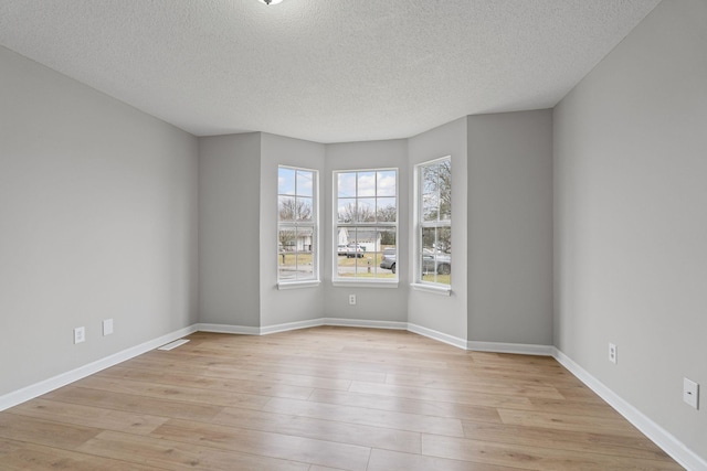 empty room featuring a textured ceiling and light hardwood / wood-style floors