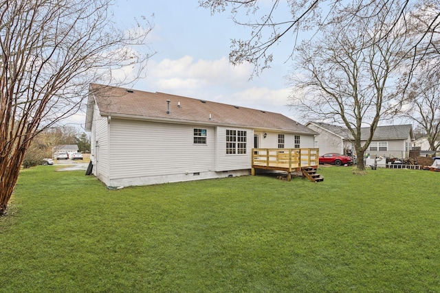 rear view of house featuring a wooden deck and a lawn