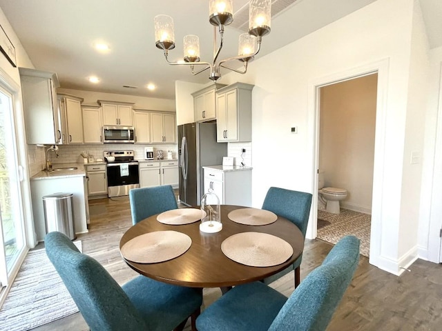 dining room featuring sink, light hardwood / wood-style flooring, and a chandelier