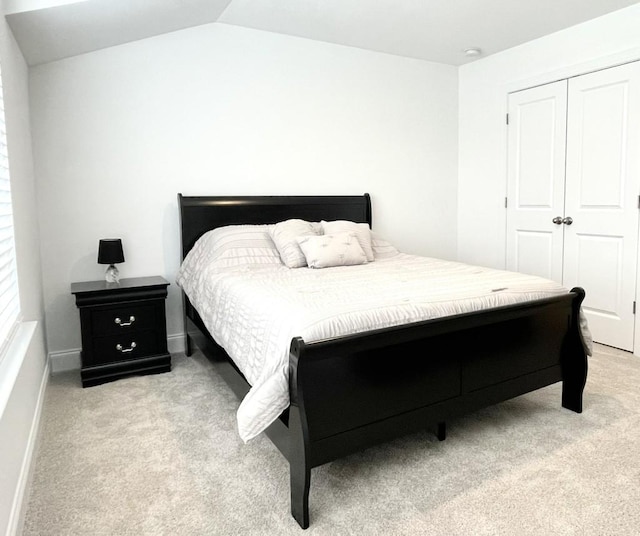 carpeted bedroom featuring vaulted ceiling and a closet