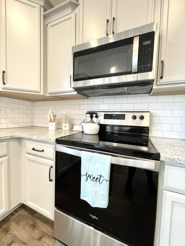 kitchen featuring light stone counters, decorative backsplash, white cabinets, and appliances with stainless steel finishes