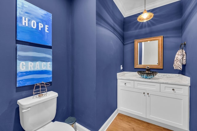 bathroom with ornamental molding, wood-type flooring, toilet, and vanity