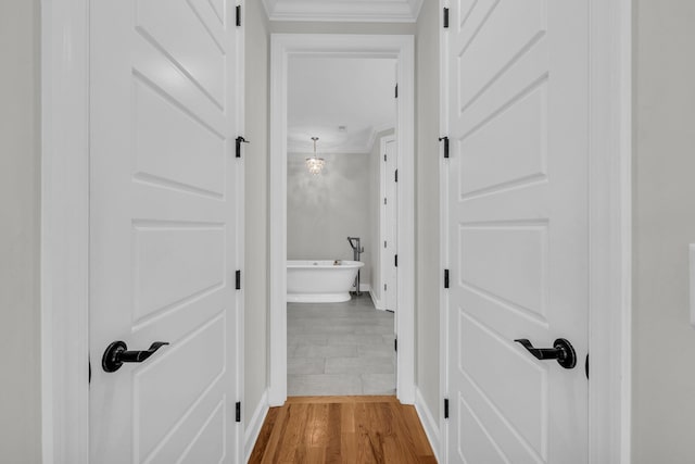 hallway featuring hardwood / wood-style flooring, ornamental molding, and a barn door