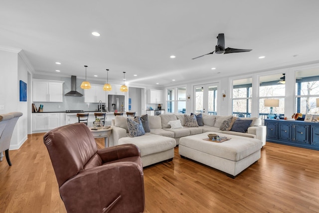 living room with crown molding, a wealth of natural light, and light hardwood / wood-style floors