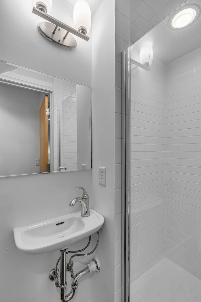 bathroom featuring a shower with shower door and sink