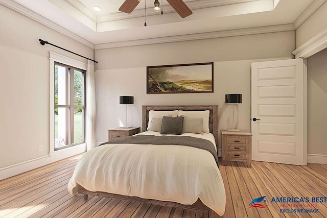 bedroom featuring ceiling fan, ornamental molding, a tray ceiling, and light hardwood / wood-style floors