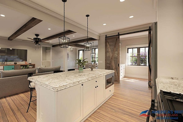 kitchen with white cabinetry, light stone counters, stainless steel microwave, and light hardwood / wood-style floors