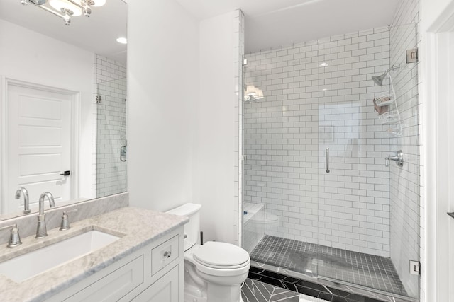 bathroom featuring vanity, a shower with door, and toilet