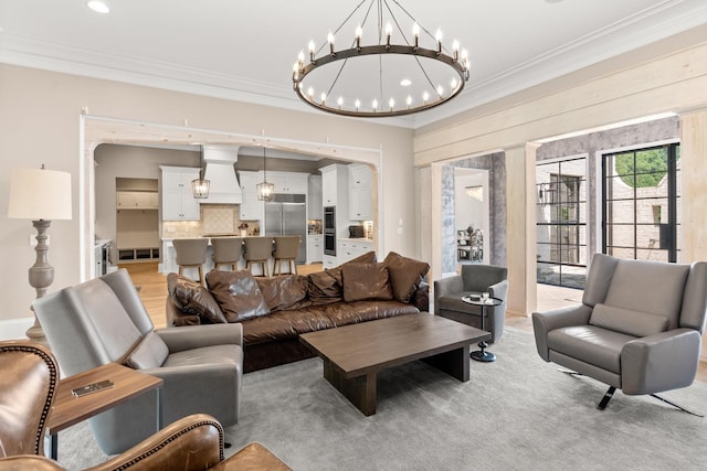 living room with ornamental molding, light wood-type flooring, and a notable chandelier