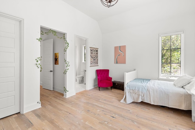 bedroom featuring vaulted ceiling, radiator, ensuite bathroom, and light hardwood / wood-style floors