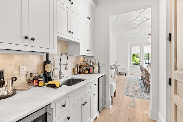 kitchen featuring white cabinetry, sink, and light stone counters