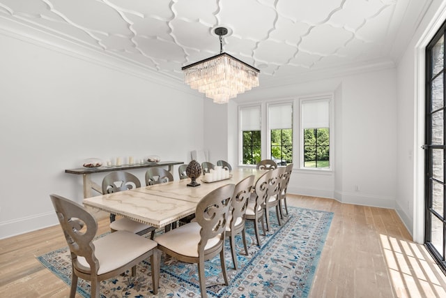 dining room with an inviting chandelier, crown molding, and light hardwood / wood-style floors