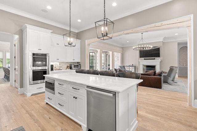 kitchen featuring stainless steel appliances, a center island, white cabinets, and decorative light fixtures