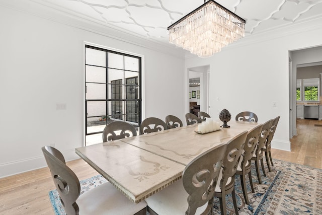 dining area with crown molding, light wood-type flooring, and a notable chandelier