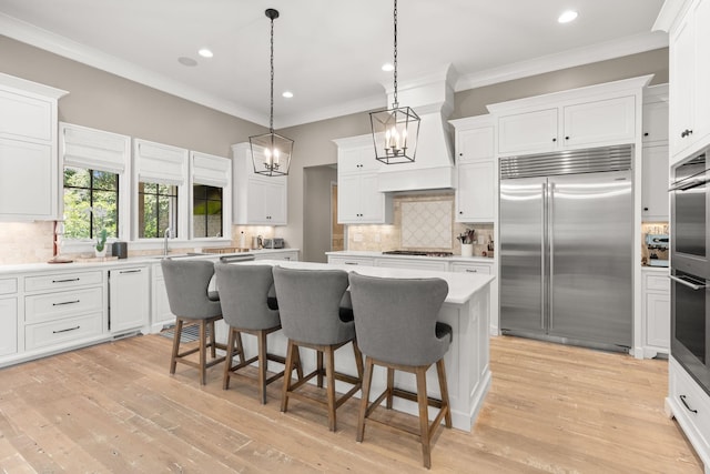 kitchen featuring white cabinetry, stainless steel appliances, a center island, and hanging light fixtures