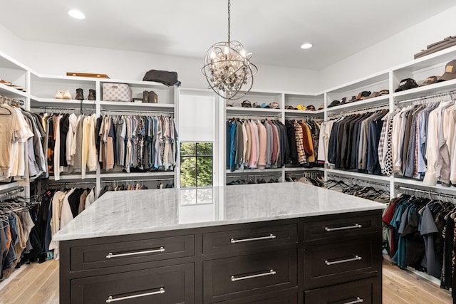 spacious closet with a chandelier and light hardwood / wood-style flooring