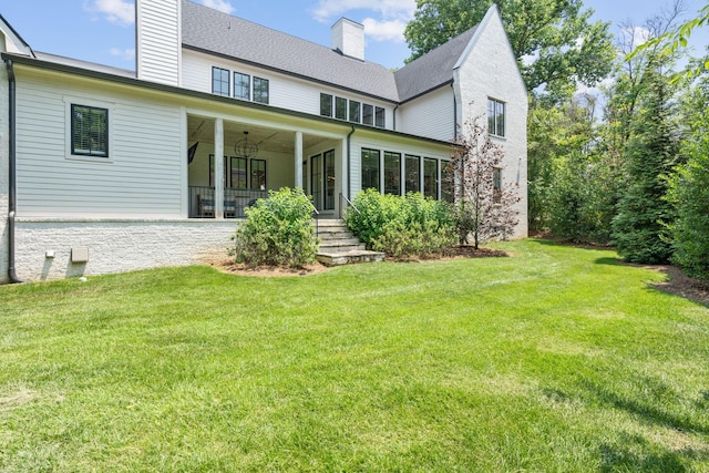 rear view of property featuring ceiling fan and a lawn