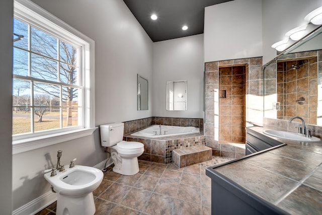 bathroom with sink, tile patterned flooring, toilet, tiled tub, and a bidet