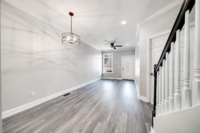 foyer entrance with ceiling fan with notable chandelier, wood-type flooring, and ornamental molding