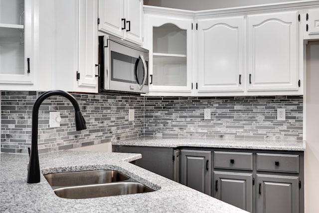 kitchen with light stone counters, sink, gray cabinets, and white cabinets