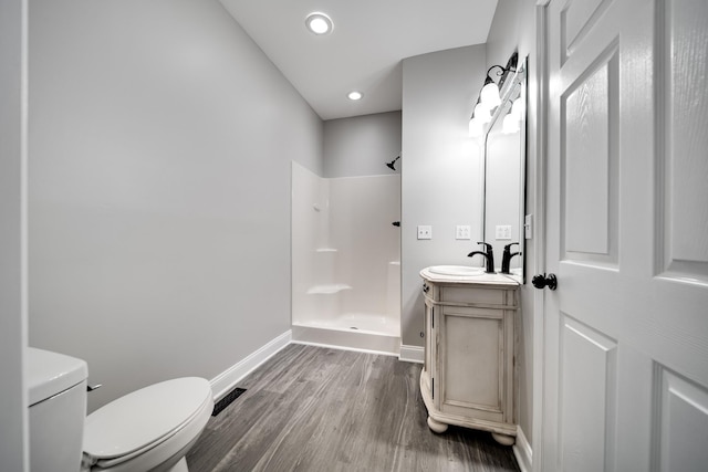 bathroom with vanity, toilet, hardwood / wood-style floors, and a shower