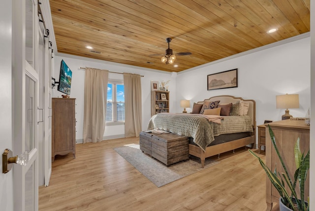 bedroom with wood ceiling, ornamental molding, a barn door, and light wood-type flooring