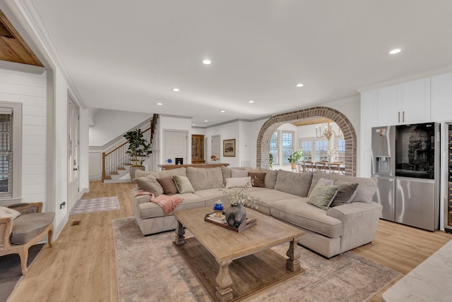 living room featuring an inviting chandelier, ornamental molding, and light hardwood / wood-style flooring