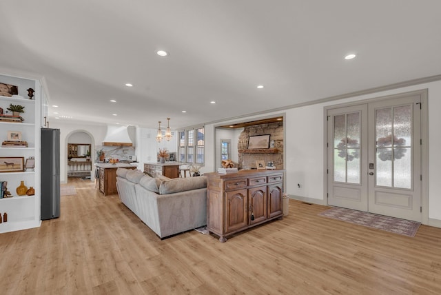 living room with crown molding, light hardwood / wood-style flooring, and french doors