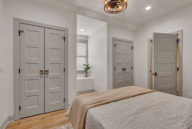 bedroom featuring two closets and light hardwood / wood-style floors