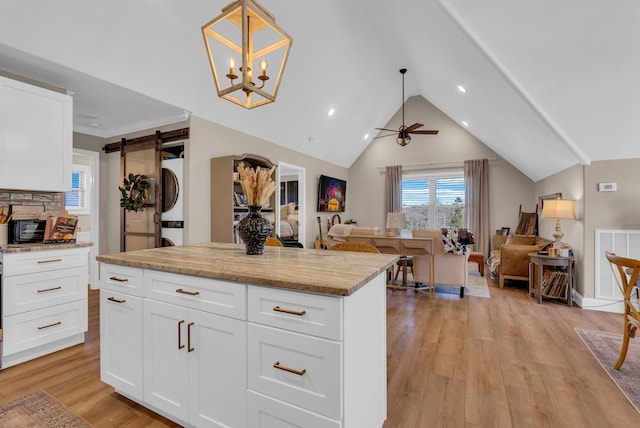 kitchen with white cabinetry, hanging light fixtures, light hardwood / wood-style flooring, a barn door, and light stone countertops