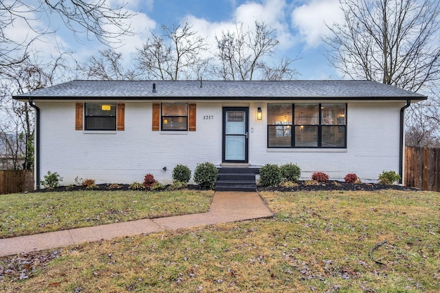 ranch-style home with a front yard, brick siding, and fence