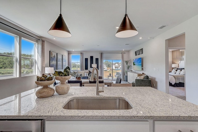 kitchen with white cabinetry, light stone countertops, sink, and decorative light fixtures