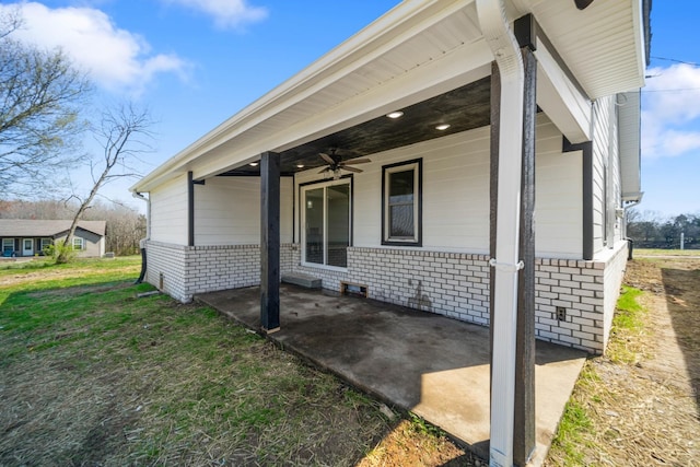 entrance to property featuring ceiling fan, a patio, and a lawn