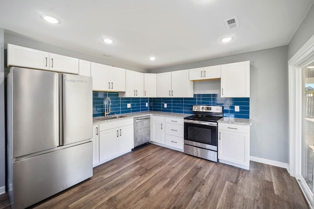 kitchen with sink, appliances with stainless steel finishes, white cabinetry, dark hardwood / wood-style floors, and decorative backsplash