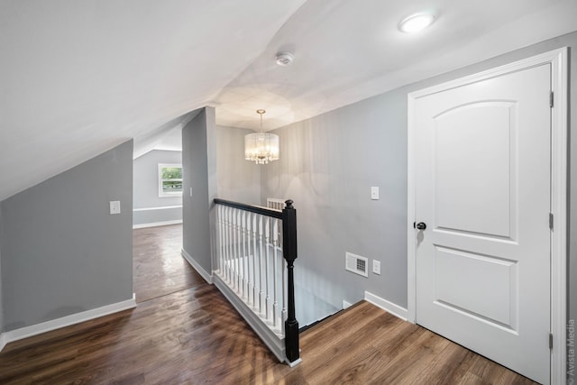 corridor with lofted ceiling, dark hardwood / wood-style floors, and a chandelier