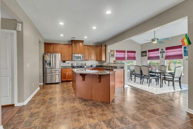 kitchen featuring vaulted ceiling, a breakfast bar area, dark stone countertops, a center island, and stainless steel appliances