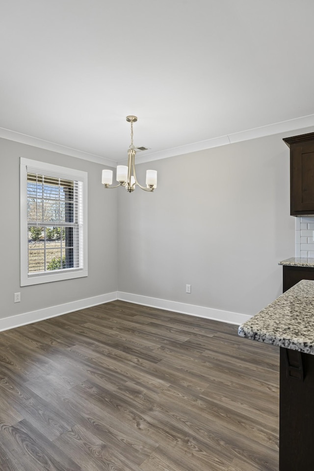 unfurnished dining area with ornamental molding, dark hardwood / wood-style floors, and a notable chandelier