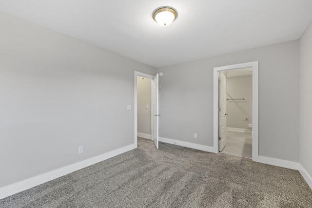 unfurnished bedroom featuring ensuite bathroom and carpet