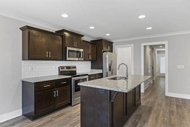 kitchen featuring sink, a breakfast bar area, stainless steel appliances, light stone countertops, and an island with sink