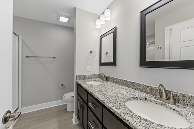 bathroom featuring vanity, a shower with shower door, and toilet