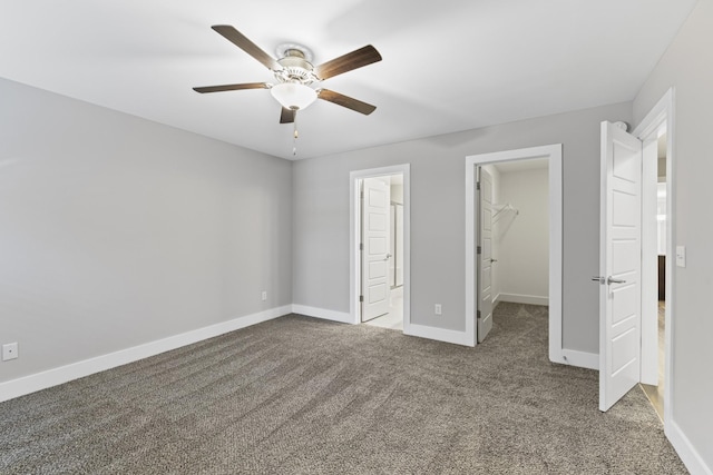 unfurnished bedroom with ensuite bathroom, a walk in closet, carpet floors, a closet, and ceiling fan