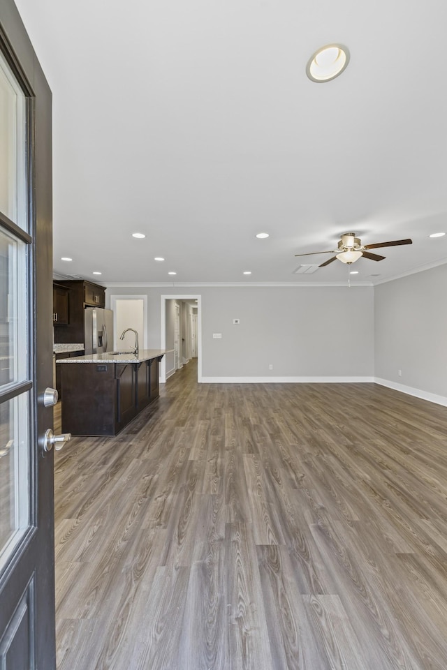 unfurnished living room featuring sink, crown molding, and light wood-type flooring