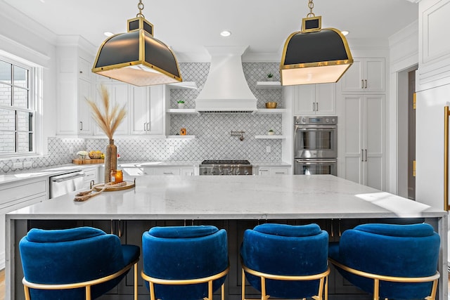 kitchen featuring stainless steel appliances, premium range hood, light stone countertops, and white cabinets