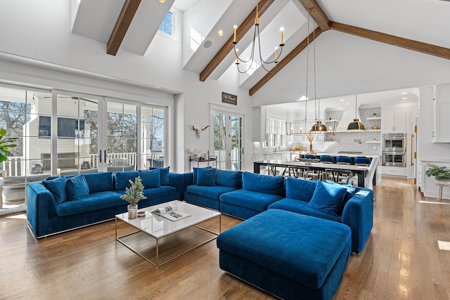 living room featuring french doors, beamed ceiling, hardwood / wood-style flooring, and a notable chandelier