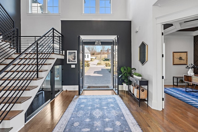 foyer entrance with beamed ceiling, wood-type flooring, coffered ceiling, and a high ceiling