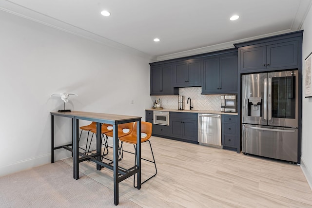 kitchen featuring sink, crown molding, stainless steel appliances, light hardwood / wood-style floors, and decorative backsplash