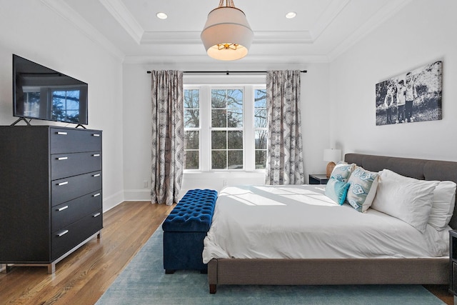 bedroom featuring hardwood / wood-style flooring, ornamental molding, and a raised ceiling