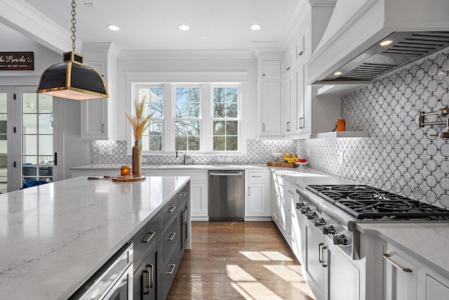 kitchen featuring premium range hood, appliances with stainless steel finishes, pendant lighting, white cabinetry, and light stone countertops